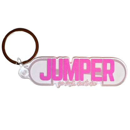 Jumper equestrian keychain. Large pink text reads “jumper” with smaller text “go fast, don’t’ die” over background image of a dee ring snaffle bit.