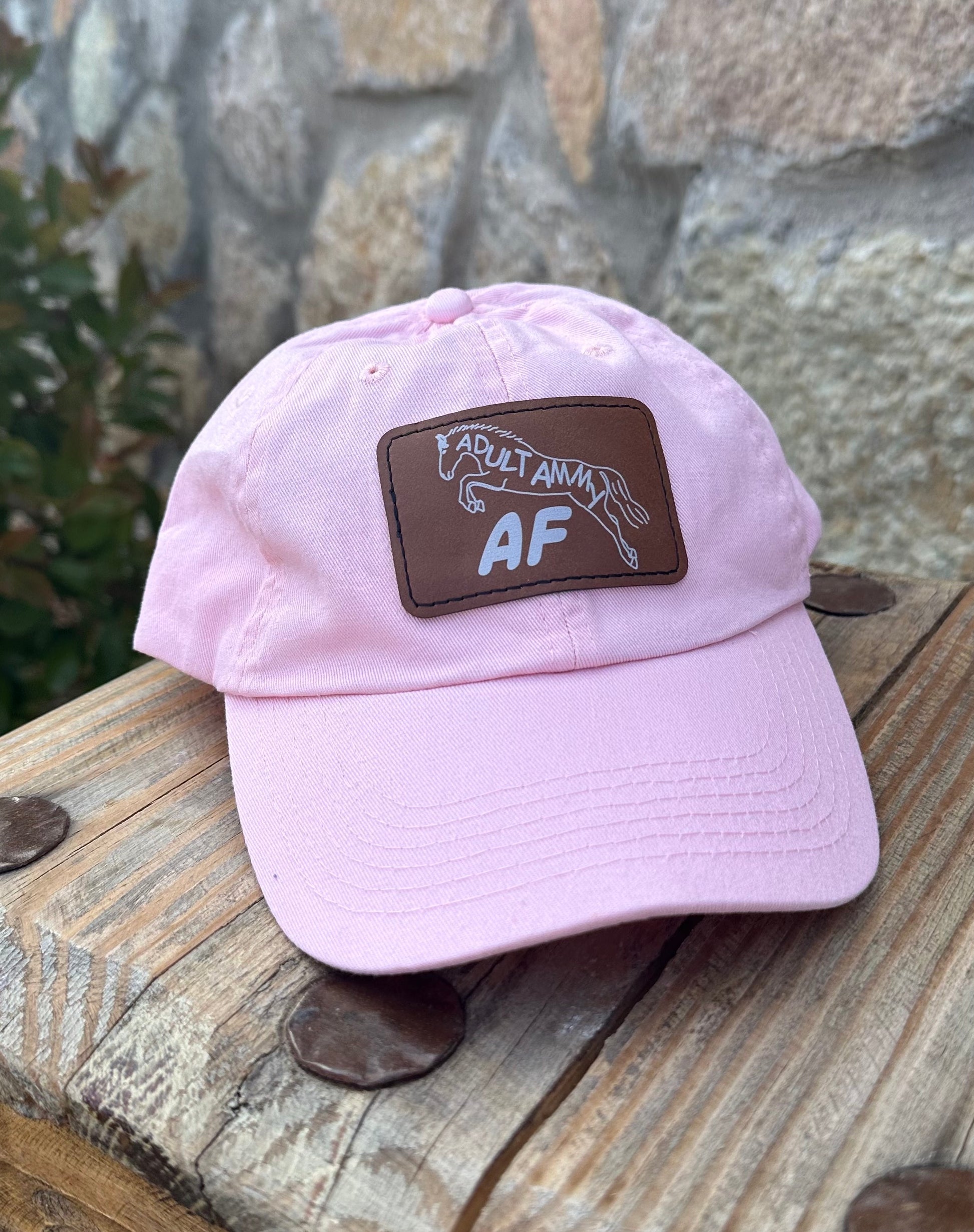 Light pink hat with brown leather patch with design of jumping horse and text Adult Ammy AF