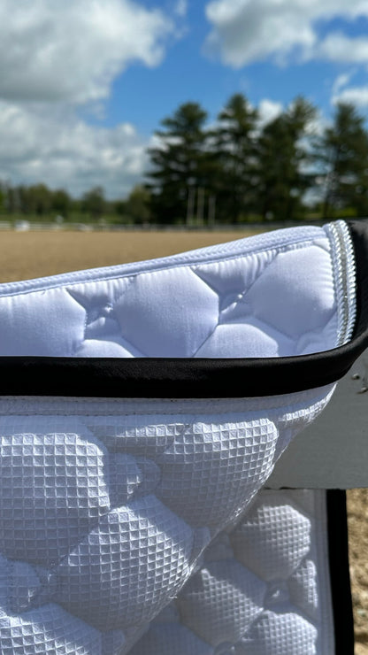 underside wicking no-rub waffle fabric on white dressage saddle pad with arena in background